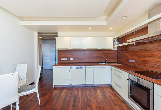 istock Modern Home L-Shaped Kitchen Interior with Wooden Flooring and White Cabinets 2205591930