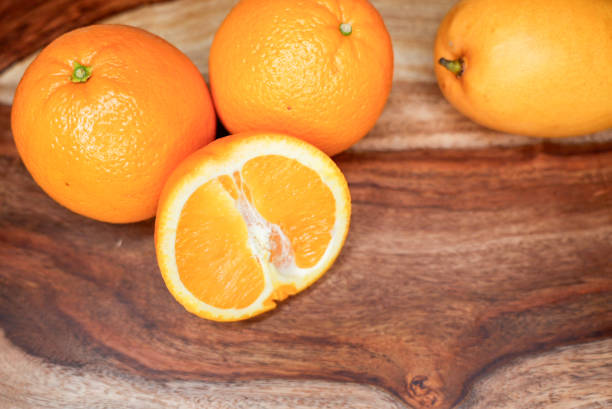 istock Whole and Sliced Oranges with a Mango on a Wooden Cutting Board 2205594522