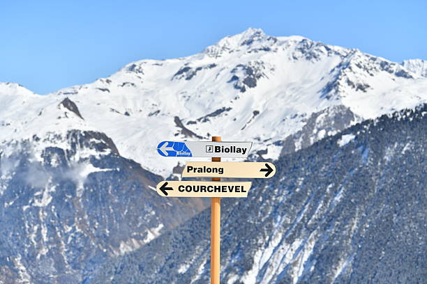 Blank yellow arrow signpost pointing left on a pole on a mountain against a blue sky