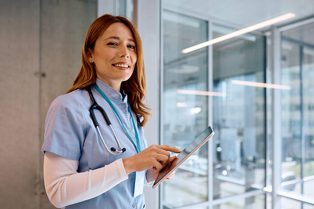 istock Happy nurse working on digital tablet in a hospital and looking at camera. 2205595614
