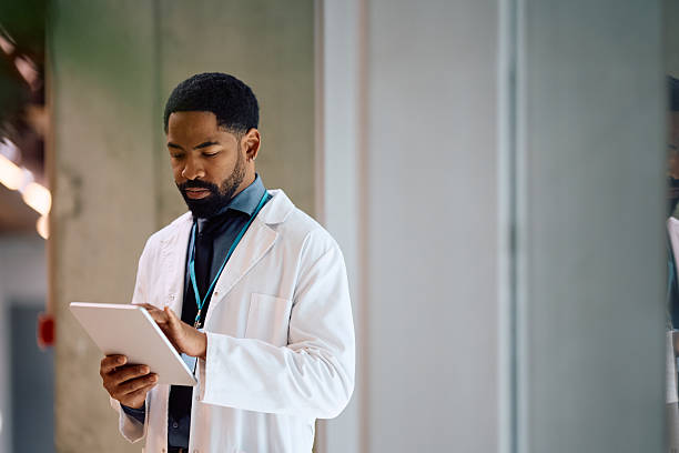 African American doctor using touchpad while working at medical clinic. Copy space.