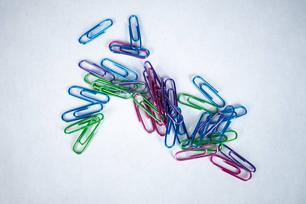 Multi-colored metal paper clips scattered on white background