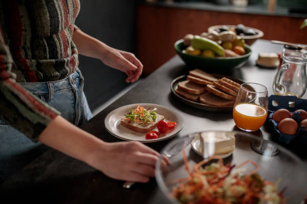 istock Woman Assembling a Sandwich in the Kitchen 2205602072