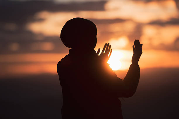 Muslim woman prayer having worship and praying with hands open doing dua to Allah at sunset Silhouette of muslim woman prayer having worship and praying with hands open doing dua to Allah at sunset . High quality photo i love allah in arabic silhouettes stock pictures, royalty-free photos & images