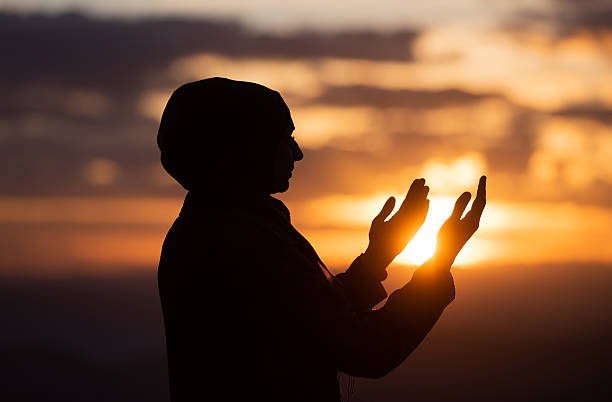 Muslim woman prayer having worship and praying with hands open doing dua to Allah at sunset Silhouette of muslim woman prayer having worship and praying with hands open doing dua to Allah at sunset . High quality photo i love allah in arabic silhouettes stock pictures, royalty-free photos & images