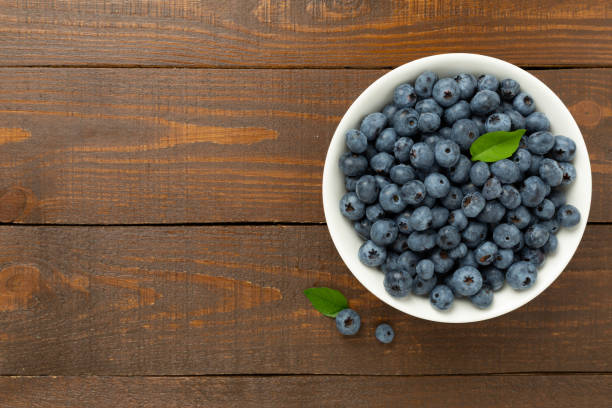 istock Bowl with fresh bright blueberries on wooden background,top view 2205607109