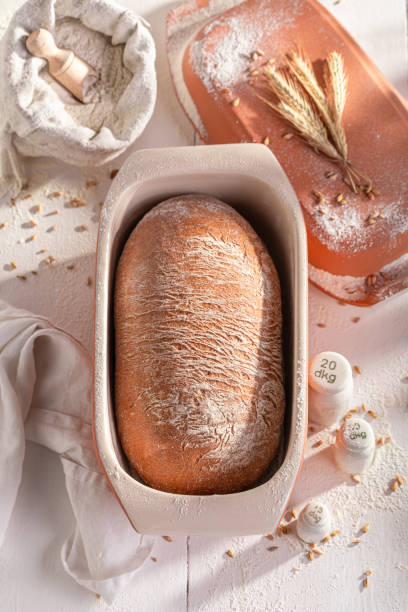 istock Homemade and fresh loaf of bread in ceramic baking tin. 2205608242