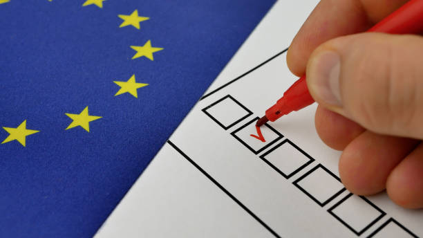 istock Hand marks choice with red marker on ballot 2205609703