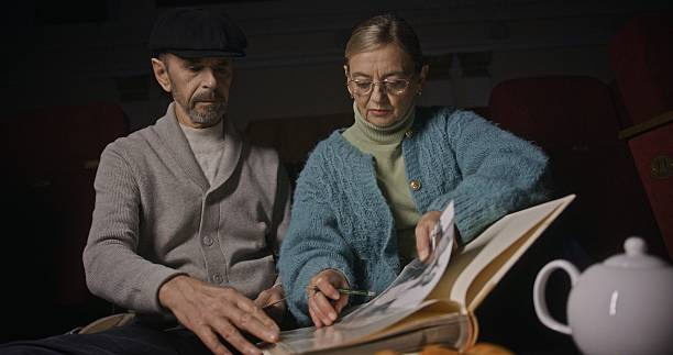 In a warm, cozy setting, a loving couple sits together reminiscing over a cherished photo book, sharing tender moments