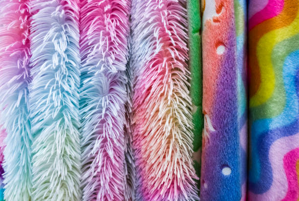Rolls of colorful and fluffy fabrics with rainbow patterns, ideal for creating cozy blankets, pillows, or other textile projects