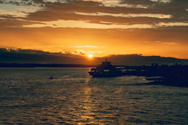 istock Ferry leaving harbor at golden orange sunset over mountains 2205611889