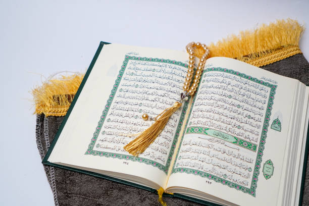 istock Open Quran with Golden Prayer Beads on a Prayer Mat 2205614411