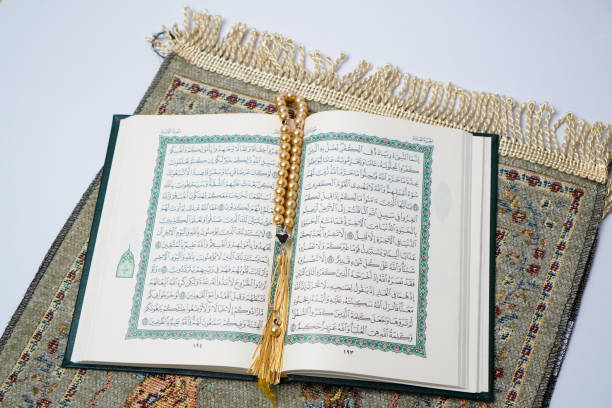 istock Open Quran with Golden Prayer Beads on a Prayer Mat 2205614438
