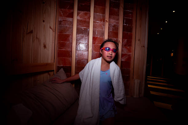A little girl is relaxing in a spa-like salt cave, the room is filled with pinky Himalayan salt. it is said halotherapy is benefit for respiration conditions, skin conditions and allergies.