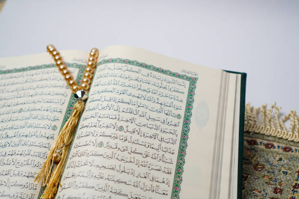 istock Open Quran with Golden Prayer Beads on a Prayer Mat 2205614456