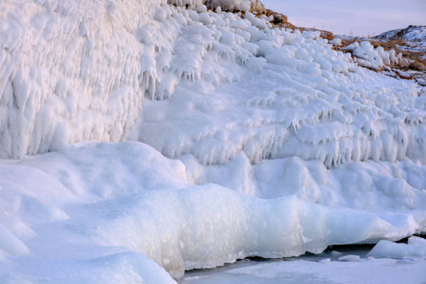 istock Lake Baikal is covered with ice and snow, thick clear blue ice. Icicles hang from the rocks. 2205615749