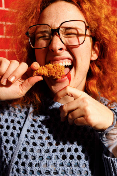 istock Redhead Woman Enjoying Spicy Fried Chicken 2205615839