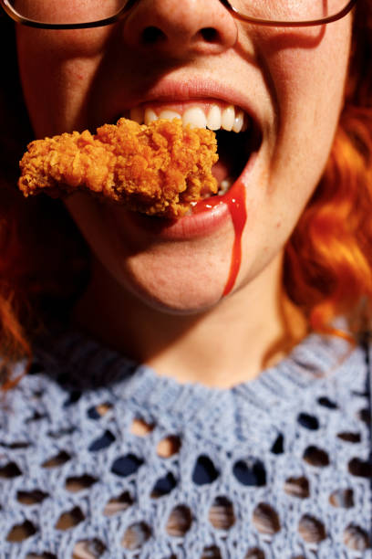 istock Redhead Woman Enjoying Spicy Fried Chicken 2205615842
