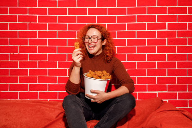 istock Redhead Woman Enjoying Spicy Fried Chicken 2205615877