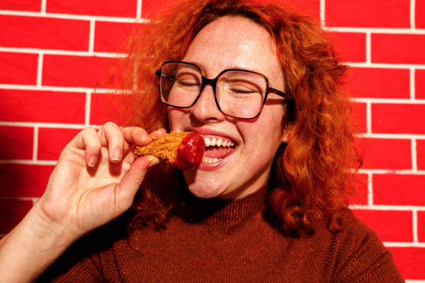 istock Redhead Woman Enjoying Spicy Fried Chicken 2205615893