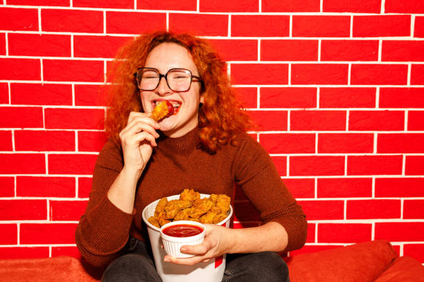 istock Redhead Woman Enjoying Spicy Fried Chicken 2205615899