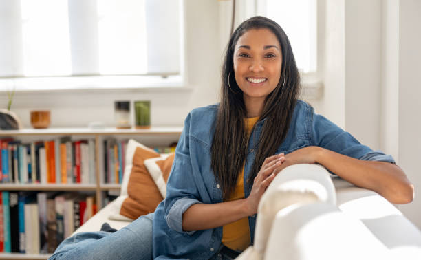 istock Beautiful woman smiling while relaxing at home on the sofa 2205618119