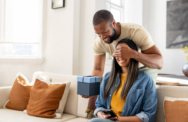istock Man surprising his girlfriend with a birthday present at home 2205619858