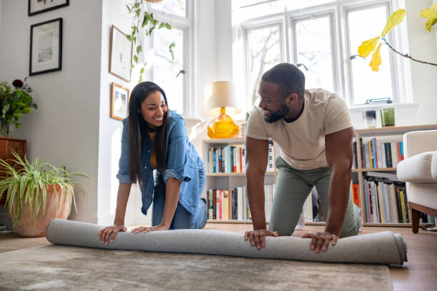 istock Happy couple unrolling a new carpet at home 2205619867