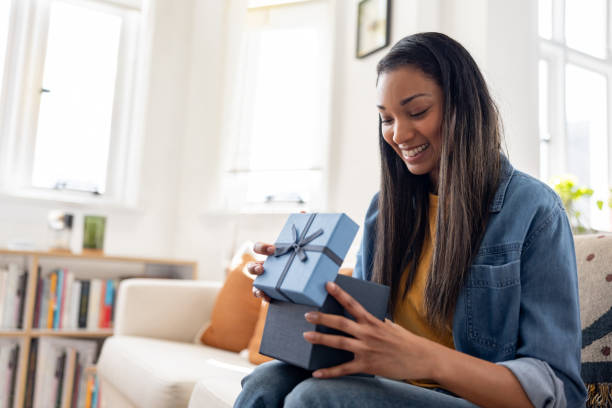 Woman smiling while opening a birthday present at home