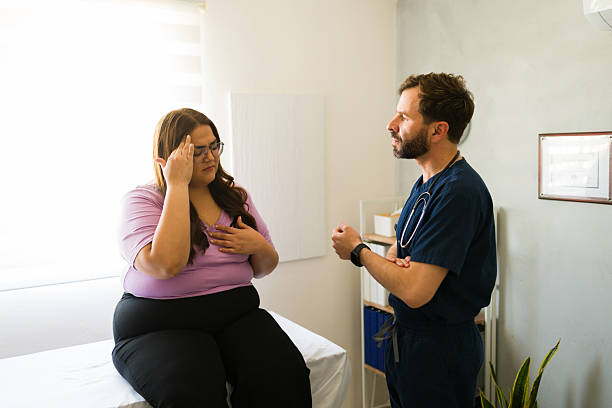 istock Obese patient communicating health concerns while seated on exam table during medical consultation with healthcare professional 2205627274