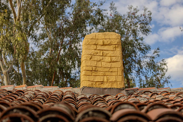 An orange color brick chimney on top of an old terracotta tile roof in Carlsbad, California.  HDR encoded.
