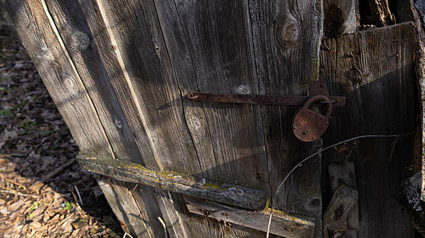 An old, weathered wooden door featuring a rusty padlock attached to it