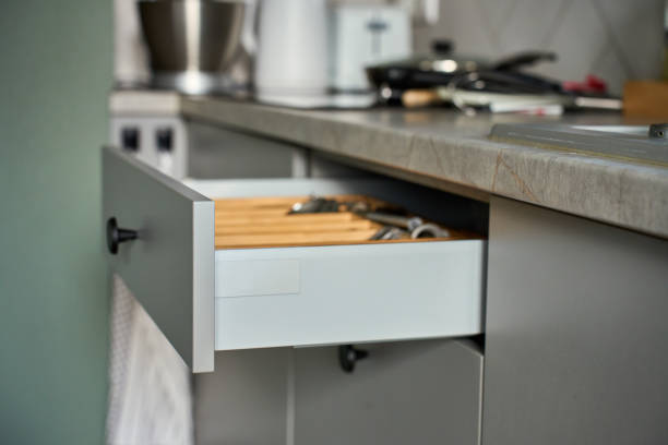 Open kitchen drawer with arranged set of cutlery and cooking utensils in wooden organizer. Contemporary kitchen cabinet. Concept of home organization and kitchen efficiency