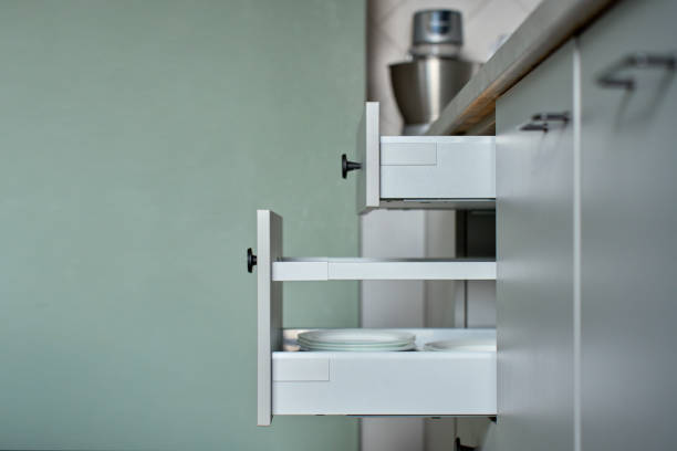 Modern kitchen with dishes and cutlery in open drawers. Contemporary kitchen cabinets. Concept of home organization and functionality interior