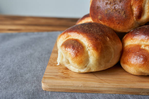 istock Freshly baked buns on a wooden cutting board on a gray background 2205641952