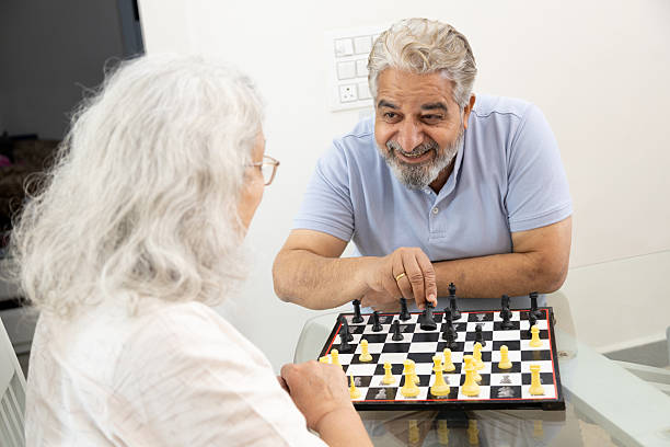 happy senior indian couple enjoying a game of chess while smiling and engaging in a friendly competition. hobby and fun activity, Retirement .life. happy senior indian couple enjoying a game of chess while smiling and engaging in a friendly competition. hobby and fun activity, Retirement .life. chess stock pictures, royalty-free photos & images
