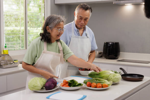 istock Elderly couple preparing a meal together in their kitchen 2205643048