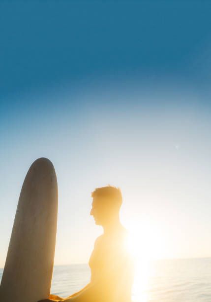 Photo of a male surfer at the beach, holding his surfboard