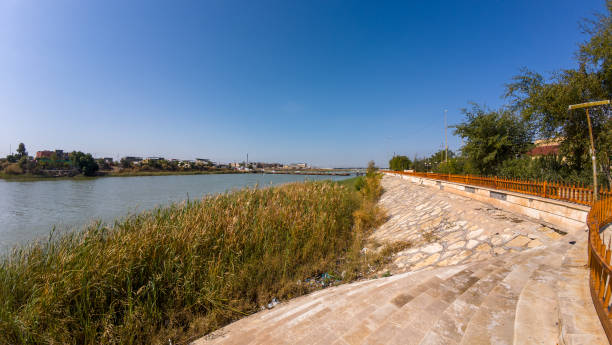 istock Scenic Riverbank with Stone Walkway and Lush Greenery 2205644929