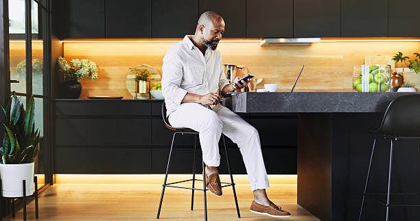 istock Black man, relax and phone for remote work at house for communication, research and schedule update. Mature person, mobile and real estate with email, feedback and property negotiation for investment 2205648989