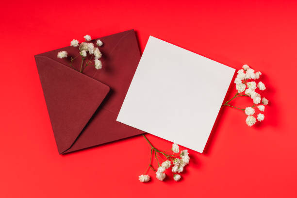 istock Red envelope, blank form and gypsophila branches on red background. Mockup for greeting card or invitation. 2205649867