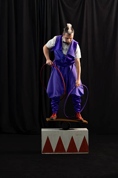 istock Circus performer balancing on rola bola and holding hoops 2205650639