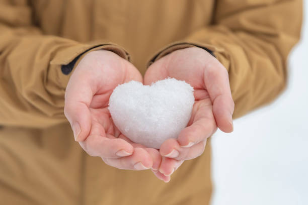 istock Woman with heart-shaped snowball 2205652370