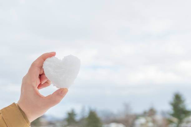 Woman's hand holding a heart-shaped snowball