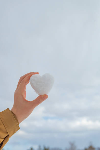 istock Woman's hand holding a heart-shaped snowball 2205652395