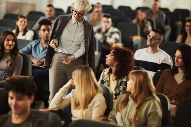istock Senior female professor using touchpad with her students on a class at lecture hall. 2205654309