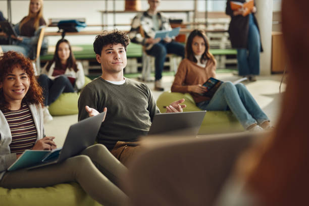istock Smiling male student talking during a class at casual classroom. 2205654819