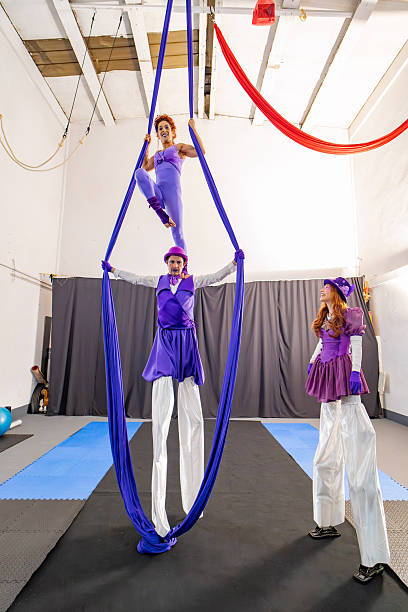 istock Circus performers practicing aerial acrobatics with purple silks and stilts 2205655872