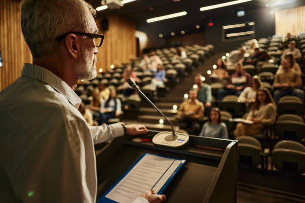 istock Mature professor giving a speech on a class at lecture hall. 2205657833