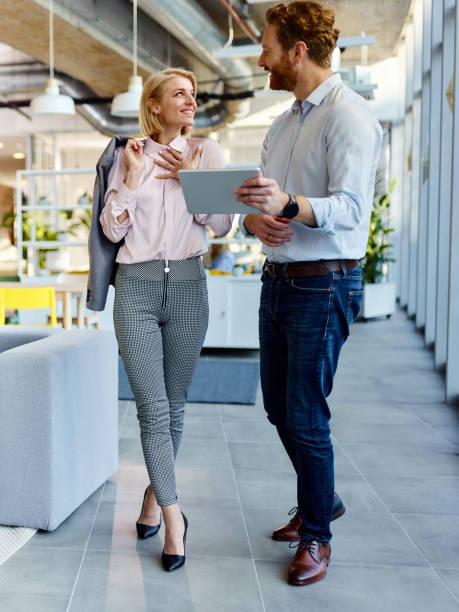 istock Happy business colleagues talking while working on touchpad in a hallway. 2205657891